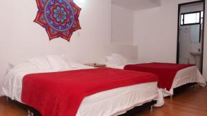 two beds in a room with red and white sheets at HOTEL Y RESTAURANTE SHALOM in Pamplona