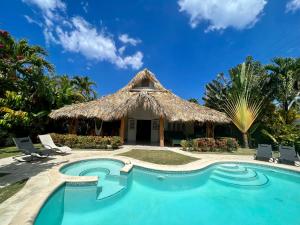 a resort with a swimming pool and a thatch hut at Maloca by Villa Clarissa8 in Las Terrenas