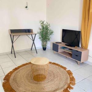 een woonkamer met een tafel en een tv bij La Gîte Le Sucrier au Lamentin -10 min du CHUM in Le Lamentin