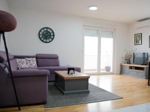 a living room with a purple couch and a table at An apartment M & K - 70 m2 in Ljubuški