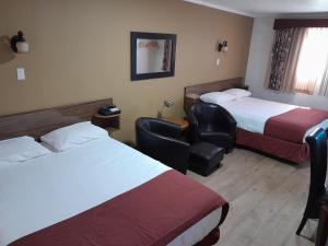 a hotel room with two beds and a chair at Travellers Motel in Cranbrook