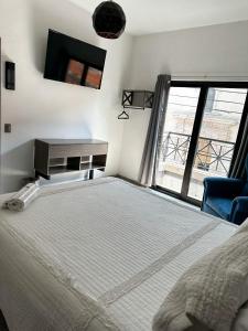 a bedroom with a bed and a desk and a window at Hotel Asís in San Juan de los Lagos
