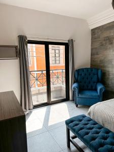 a bedroom with a bed and a chair and a window at Hotel Asís in San Juan de los Lagos