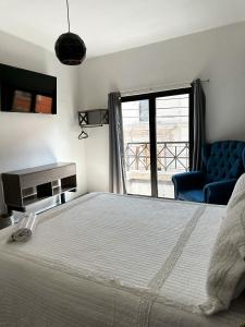 a bedroom with a large bed and a blue chair at Hotel Asís in San Juan de los Lagos
