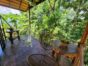 a porch with a hammock and a table and chairs at La Fortuna Rainforest Glass Cabin With Suite in Fortuna