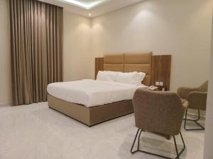 1 dormitorio con 1 cama, escritorio y sillas en فندق دره الراشد للشقق المخدومه en Riad