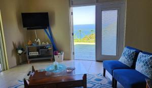 sala de estar con sofá, mesa y ventana en OCEAN VIEW VILLA, Tortola, British Virgin Islands, en Tortola Island