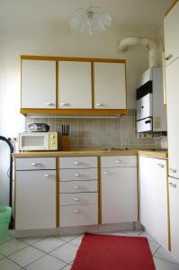 cocina con armarios blancos y microondas en Apartment Trappelgasse, en Viena