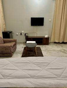a bedroom with a bed and a couch and a tv at Riya Villa - Entire Villa (Kaashi Flora) in Varanasi