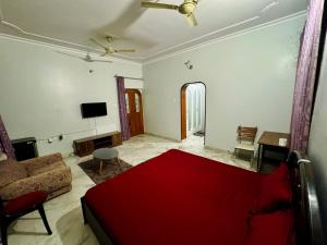 uma sala de estar com uma cama vermelha e um sofá em Riya Villa - Entire Villa (Kaashi Flora) em Varanasi