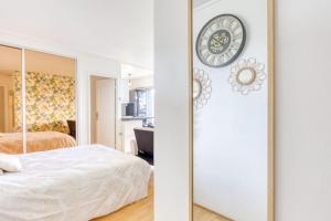 sypialnia z lustrem i zegarem na ścianie w obiekcie *Le sublime* vue sur la tour Eiffel / JO 2024 w mieście Saint-Maurice