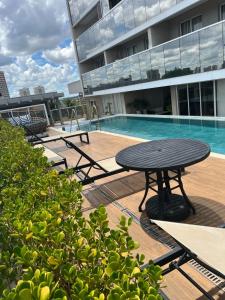 una mesa y bancos junto a una piscina en un edificio en Loft alto padrão, último andar Uptown c/ garagem, en Araçatuba