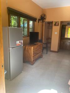 a kitchen with a refrigerator and a tv in it at R&V VILLA in Negril