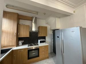 uma cozinha com um frigorífico de aço inoxidável e armários de madeira em 5 Bedroom, 2 bath Leeds Hideaway Haven em Headingley