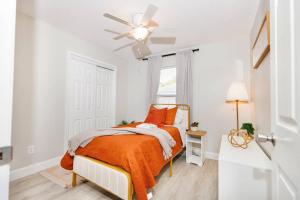 um quarto branco com uma cama com um cobertor laranja em Entire 2 Bd Home w/ Murals + Parking by Downtown em Orlando