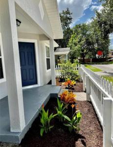 una casa blanca con una puerta azul y algunas plantas en Entire 2 Bd Home w/ Murals + Parking by Downtown, en Orlando