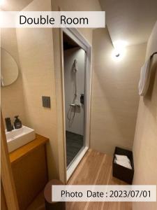 a bathroom with a shower and a sink and a mirror at HOTEL TOMOS ASAKUSA in Tokyo