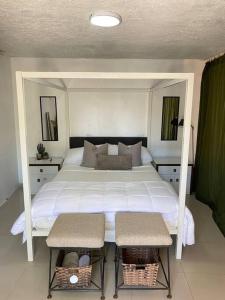 1 Schlafzimmer mit einem großen weißen Bett mit 2 Stühlen in der Unterkunft Bleesed House in Monte Adentro