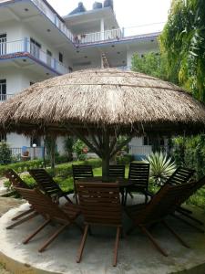 a group of chairs and a table with a straw umbrella at Hotel Shiva's Dream in Sauraha