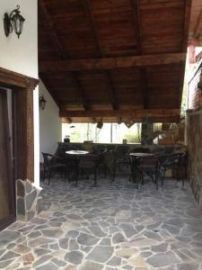 a patio with tables and chairs on a stone floor at Pensiunea Rustic in Borşa +29 photos