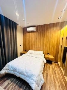 ルクソールにあるFarida Habu Palace Hotelの木製の壁のベッドルーム1室(白い大型ベッド1台付)