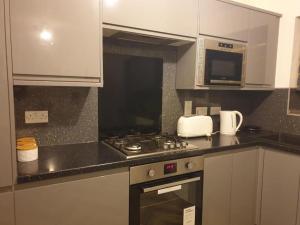 a kitchen with a stove top oven and a microwave at Oasis Abode @ Ashover Newcastle in Kenton