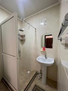 uma casa de banho com um lavatório e um chuveiro com um espelho. em Гостевой дом Вояж em Karakol