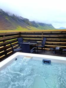 una vasca idromassaggio su una terrazza con sedie e tavolo di Green Farm Stay with private hot tub a Hvolsvöllur