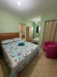 a bedroom with a bed and a pink chair at Hospedagem Zefino in Cunha