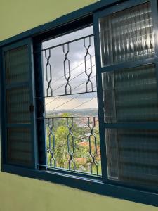 a window with a view of a field through it at Hospedagem Zefino in Cunha