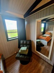a bedroom with a mirror and a chair and a bed at Green Farm Stay with private hot tub in Hvolsvöllur