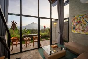 a living room with a large window with a table and chairs at Mountain Peak Kintamani in Kintamani
