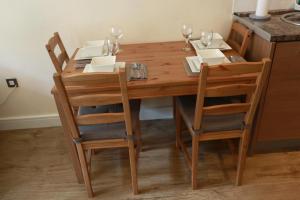 a wooden table with chairs and wine glasses on it at Luxury Apartment New Street Birmingham Feel At Home in Birmingham