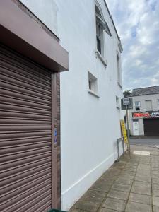 a white building with a garage door next to a street at Town Centre Apartment, 4 Beds, 1 Bathroom in Cheltenham