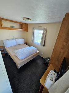 a small bedroom with a bed and a television at Caravan holiday let 2 bedroom happy days SOUTH chapel saint Leonards 05 in Chapel Saint Leonards