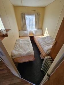 a small room with two beds and a window at Caravan holiday let 2 bedroom happy days SOUTH chapel saint Leonards 05 in Chapel Saint Leonards