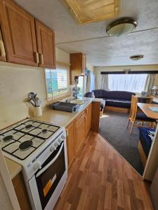 a kitchen with a stove top oven next to a living room at Caravan holiday let 2 bedroom happy days SOUTH chapel saint Leonards 05 in Chapel Saint Leonards