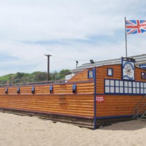 a building on the beach with a flag on it at Caravan holiday let 2 bedroom happy days SOUTH chapel saint Leonards 05 in Chapel Saint Leonards +7 photos