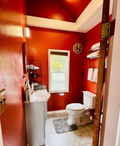 a red bathroom with a toilet and a sink at Bridge Tender Shack with hot tub on deck in La Conner