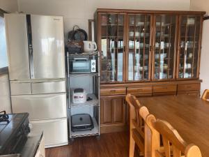 a kitchen with a wooden table and a refrigerator at 古民家のお宿ふうす in Amami