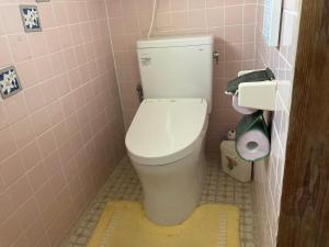 a bathroom with a white toilet in a pink bathroom at 古民家のお宿ふうす in Amami