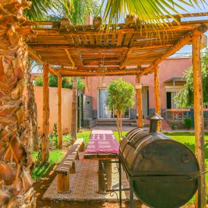 a wooden pergola with a bench and a grill at Hotel Jnane riad in Marrakech