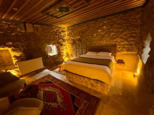 1 dormitorio con cama y pared de piedra en Euphoria Cave House en Nar