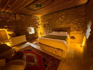 NarにあるEuphoria Cave Houseのベッドと石の壁のある寝室