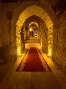 un couloir avec un tapis rouge dans un tunnel en pierre dans l'établissement Euphoria Cave House, à Nar