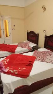 una camera con tre letti con lenzuola rosse di سيوة تورز للسياحة العلاجية a Siwa