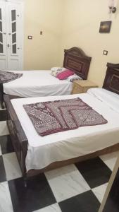 2 letti in una camera con pavimento a scacchi di سيوة تورز للسياحة العلاجية a Siwa