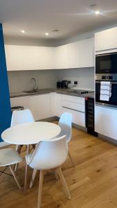 uma cozinha com uma mesa e cadeiras brancas e um fogão em 310 Arden Gate em Birmingham