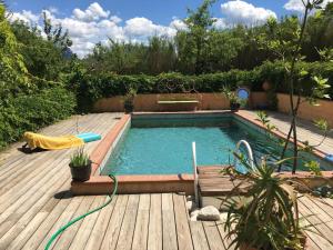 una piscina en una terraza con una terraza de madera en La petite maison de la ferme rose en Moustiers-Sainte-Marie