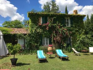een huis met twee stoelen en een tafel in de tuin bij La petite maison de la ferme rose in Moustiers-Sainte-Marie